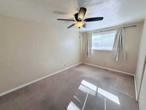 Carpeted empty room with a textured ceiling and a ceiling fan