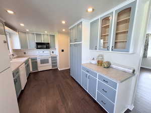 Kitchen with light countertops, white appliances, tasteful backsplash, dark wood-style floors, and recessed lighting