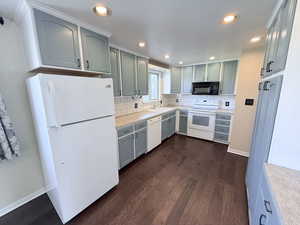 Kitchen featuring white appliances, dark wood finished floors, backsplash, and recessed lighting