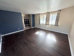 Empty room with dark wood-type flooring and a textured ceiling