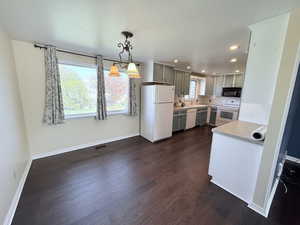 Kitchen featuring light countertops, white appliances, tasteful backsplash, dark wood-type flooring, and gray cabinets