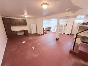 Below grade area featuring a textured ceiling and freestanding refrigerator