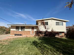 Tri-level home featuring brick siding, a front lawn, and a porch