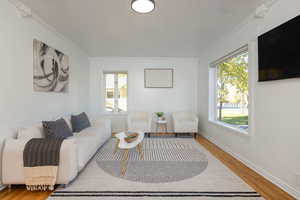 Living area with wood finished floors and crown molding