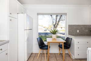 Dining space featuring light tile patterned flooring and crown molding