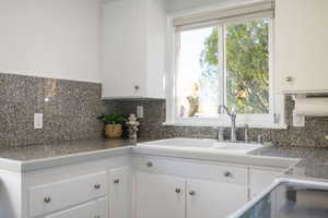 Kitchen featuring tile counters, white cabinetry, backsplash, and range with electric stovetop