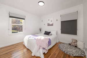 Bedroom with ornamental molding and wood finished floors