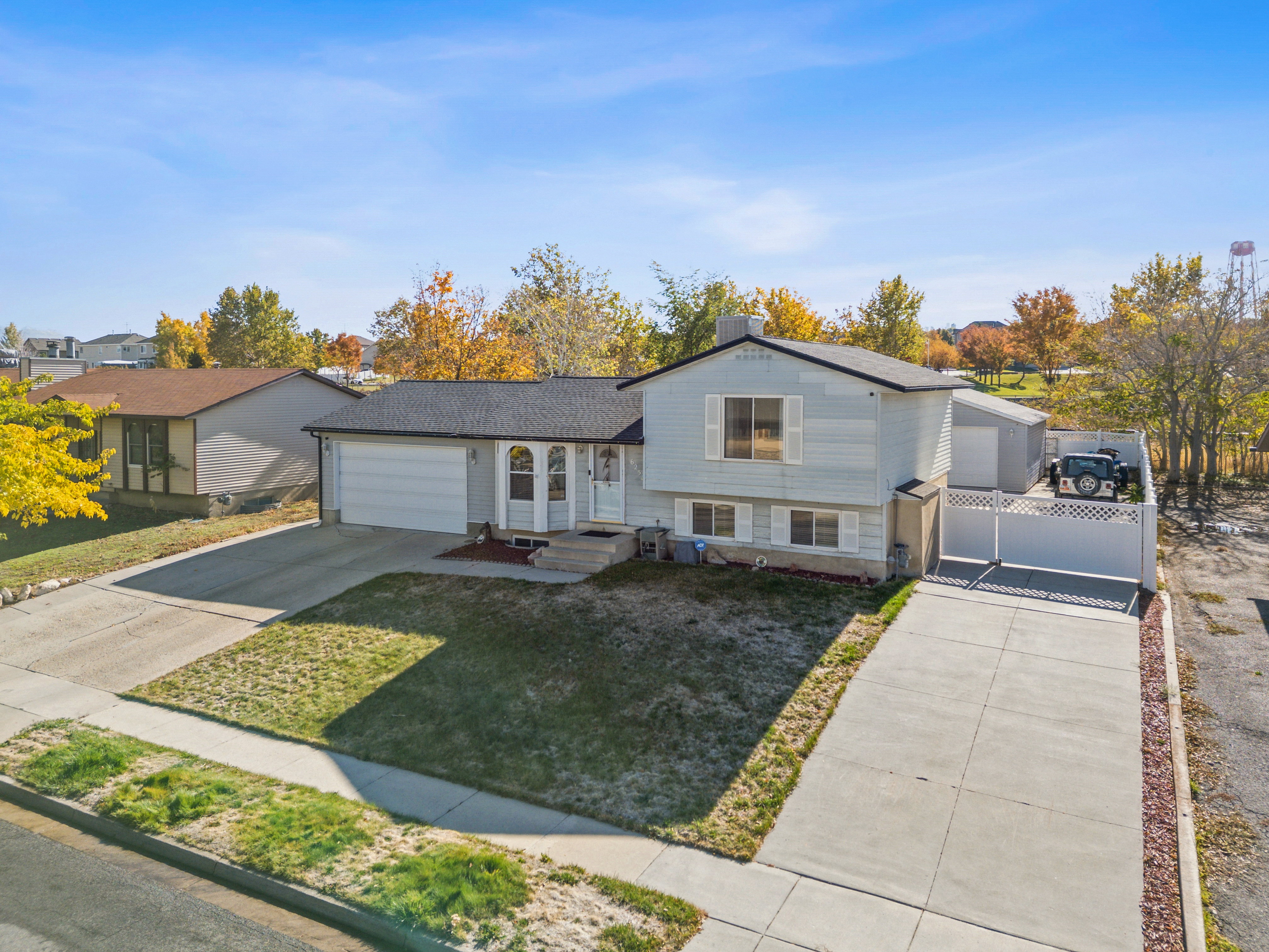 Tri-level home featuring driveway, a gate, and a front yard