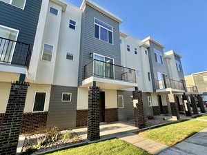 View of home's exterior featuring brick siding, stucco siding, a balcony, and a residential view