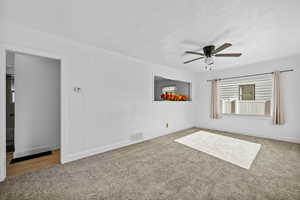 Living room featuring a textured ceiling, carpet, and a ceiling fan