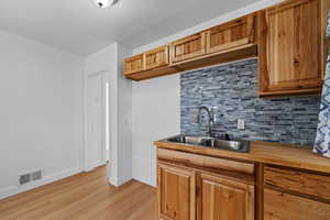 Kitchen featuring tasteful backsplash, light wood-type flooring, and brown cabinetry