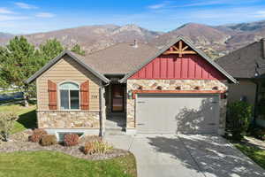 Craftsman inspired home featuring stone siding, a shingled roof, a mountain view, concrete driveway, and an attached garage