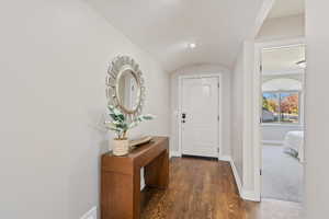 Foyer featuring dark wood-style floors and vaulted ceiling
