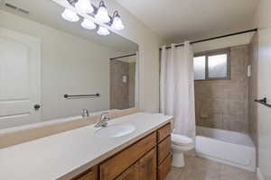 Bathroom featuring vanity, shower / tub combo with curtain, and light tile patterned floors