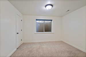 Empty room featuring light carpet and a textured ceiling