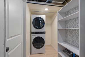 Laundry room with estacked washer and dryer and light wood finished floors