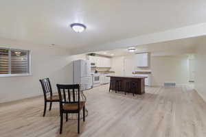 Dining space featuring light wood finished floors, a textured ceiling, and recessed lighting