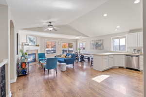Living room with light wood-type flooring, lofted ceiling, recessed lighting, a tiled fireplace, and ceiling fan
