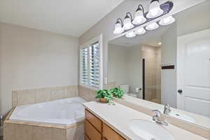 Full bathroom featuring a bath, vanity, and a tile shower