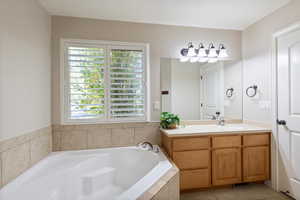 Bathroom with a bath, vanity, and light tile patterned flooring