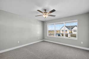 Empty room featuring carpet flooring and a ceiling fan
