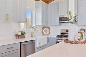 Kitchen featuring stainless steel appliances, light stone countertops, gray cabinets, decorative backsplash, and wooden ceiling