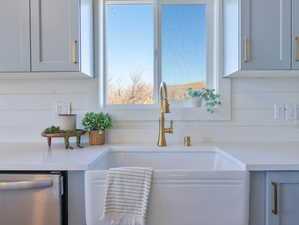 Kitchen view of dishwasher and light stone counters