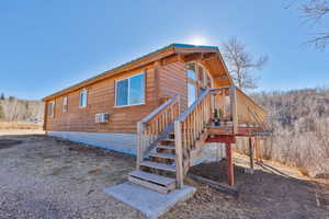 Back of house with a metal roof, a forest view, and stairway