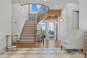 Stairs with recessed lighting, wood finished floors, and a towering ceiling