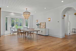 Dining area with arched walkways, light wood-type flooring, recessed lighting, and wooden ceiling