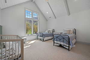 Carpeted bedroom with beamed ceiling, high vaulted ceiling, and a crib
