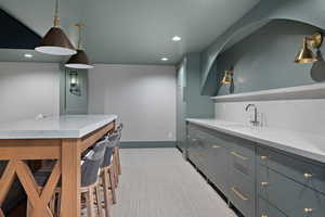 Bar area with light stone counters, open shelves, pendant lighting, recessed lighting, and gray cabinets