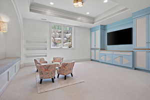 Living area featuring light carpet, a raised ceiling, ornamental molding, and recessed lighting