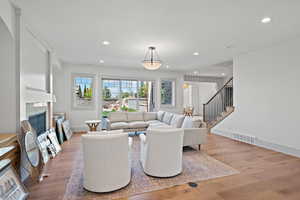 Living area featuring light wood-type flooring, recessed lighting, stairs, and a fireplace