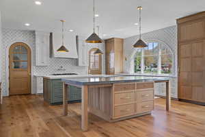 Kitchen featuring wallpapered walls, pendant lighting, recessed lighting, light wood finished floors, and light stone counters