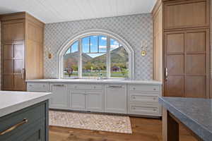 Kitchen featuring a mountain view, white cabinets, wood finished floors, light stone countertops, and wooden ceiling