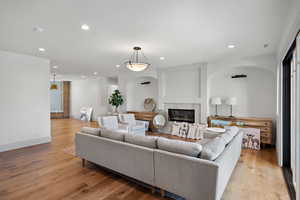 Living room featuring recessed lighting, light wood-style flooring, and a fireplace