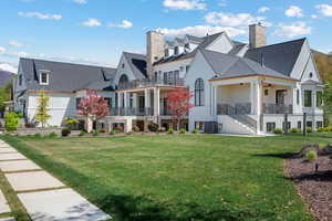 View of front of house featuring a chimney, a front lawn, stairs, a balcony, and roof with shingles