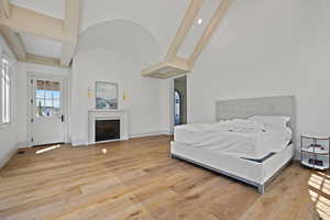 Bedroom featuring light wood-style floors, vaulted ceiling, and a fireplace