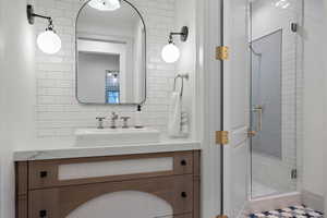 Bathroom with vanity, a shower stall, and backsplash