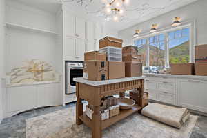 Kitchen featuring white cabinetry, a mountain view, a chandelier, white oven, and wood walls