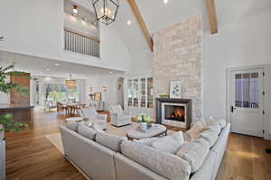 Living room featuring high vaulted ceiling, a fireplace, beamed ceiling, recessed lighting, and wood finished floors