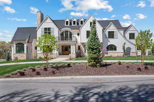 View of front facade featuring board and batten siding, stone siding, a balcony, and a chimney