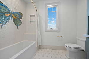 Bathroom featuring shower / bathtub combination with curtain and light tile patterned flooring