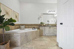 Primary bathroom featuring vanity, a garden tub, and light tile patterned flooring