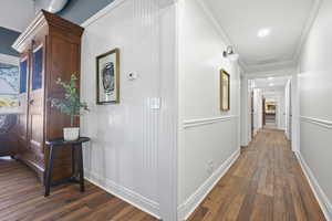 Hall featuring dark wood-type flooring, crown molding, and recessed lighting