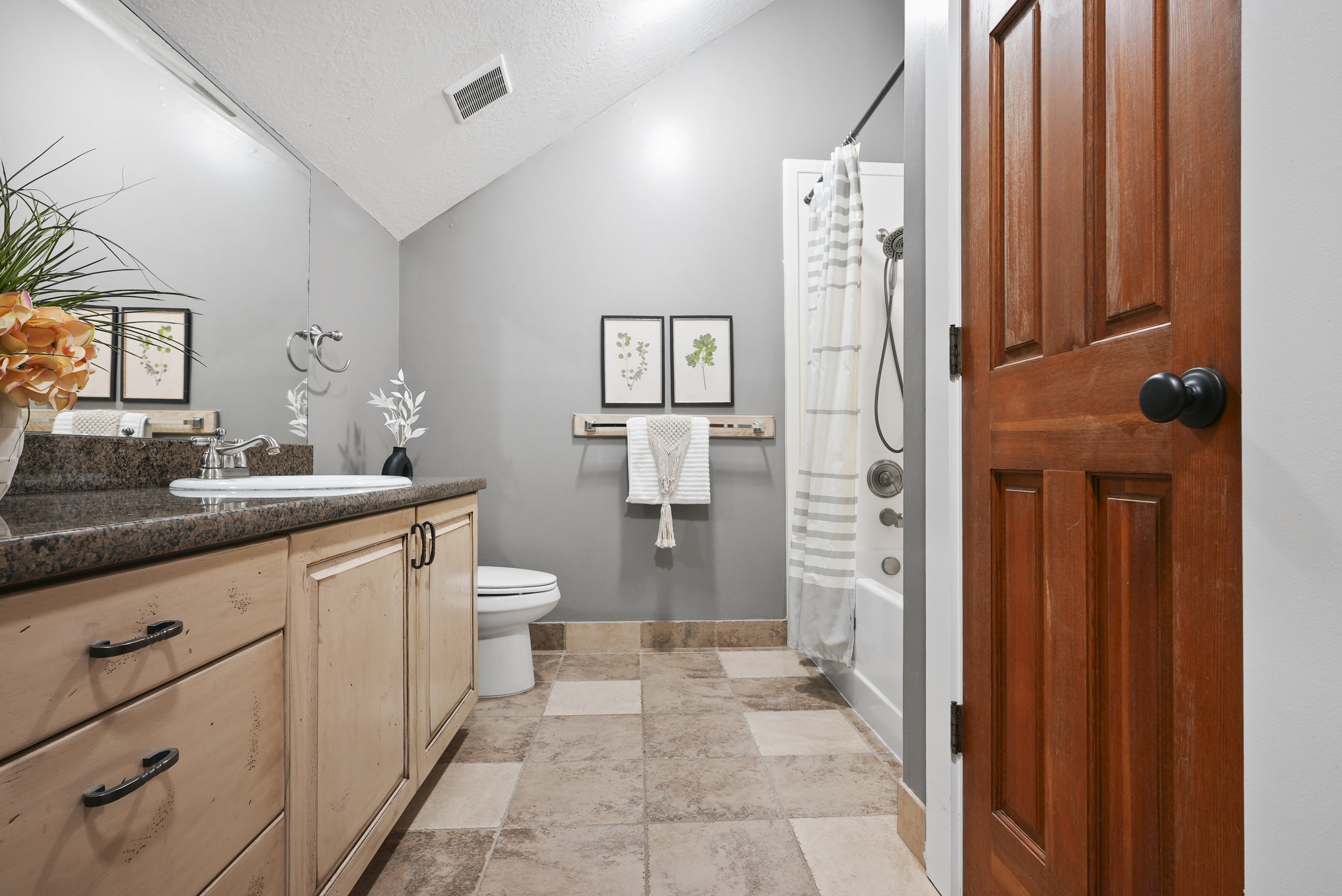 Bathroom featuring vanity, a textured ceiling, shower / bath combo, and lofted ceiling