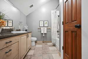 Bathroom featuring vanity, a textured ceiling, shower / bath combo, and lofted ceiling