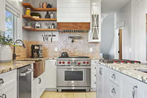 Kitchen featuring white cabinetry, light stone countertops, and high-end stainless-steel appliances