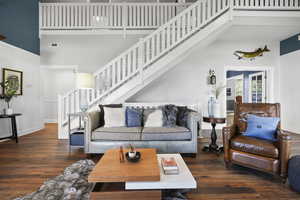 Living room with stairway, dark wood-style floors, and a towering ceiling